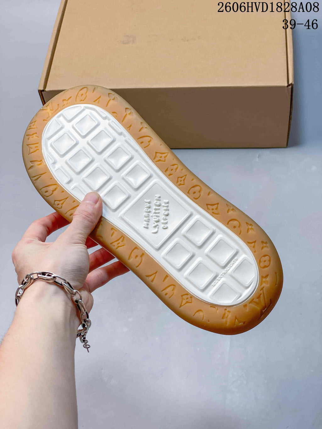 Underside of a sneaker showing a white patterned center and gum-colored outsole