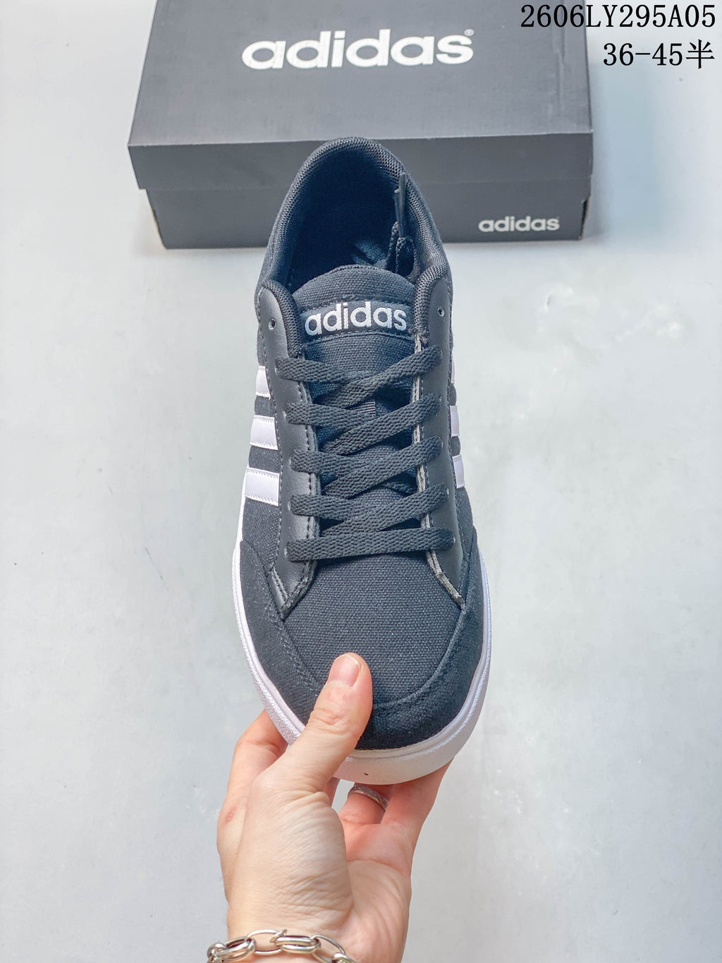 Front view of a charcoal gray Adidas lace-up sneaker with white side stripes.