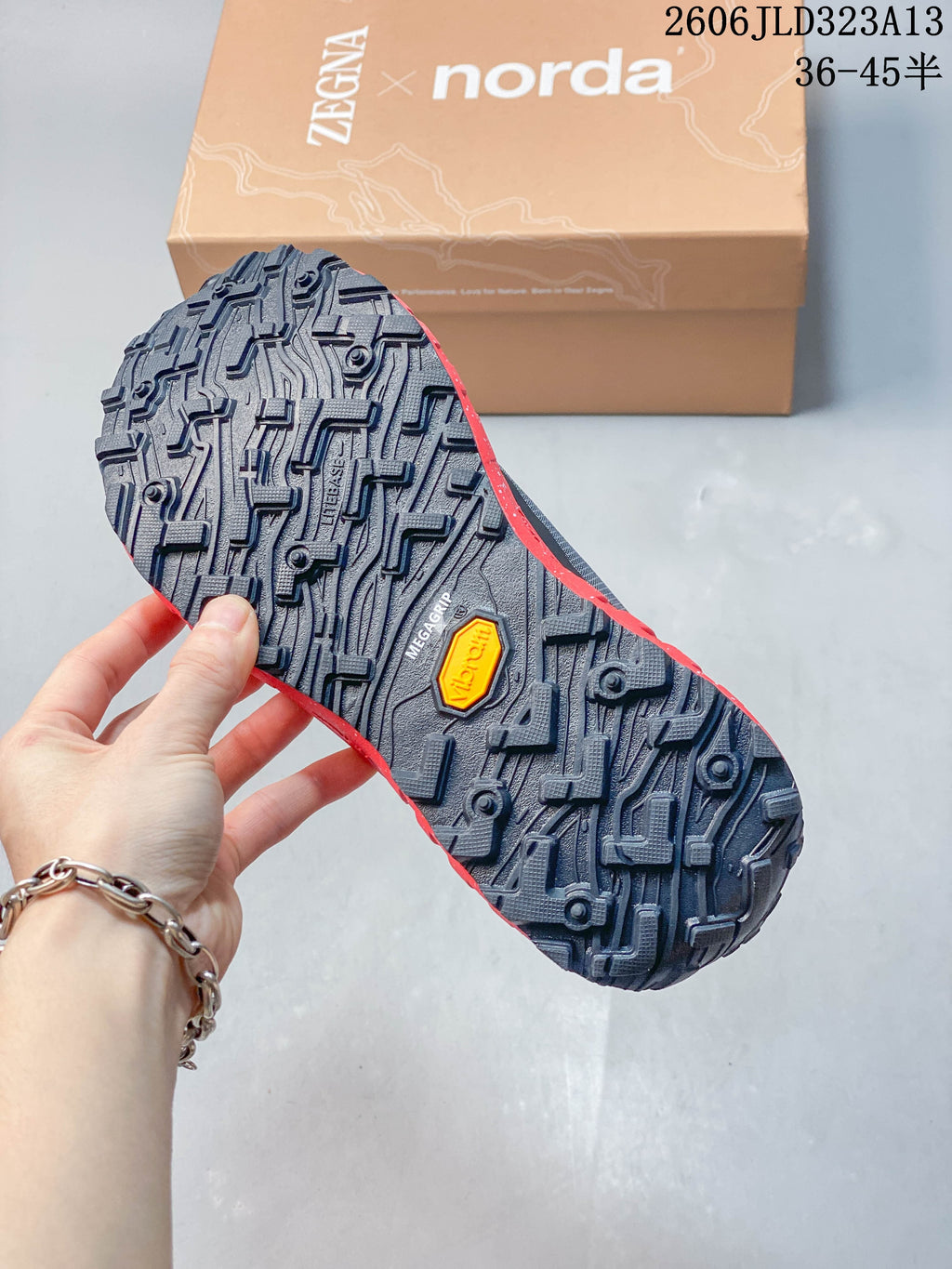 Close-up of the lugged outsole on a charcoal and red shoe