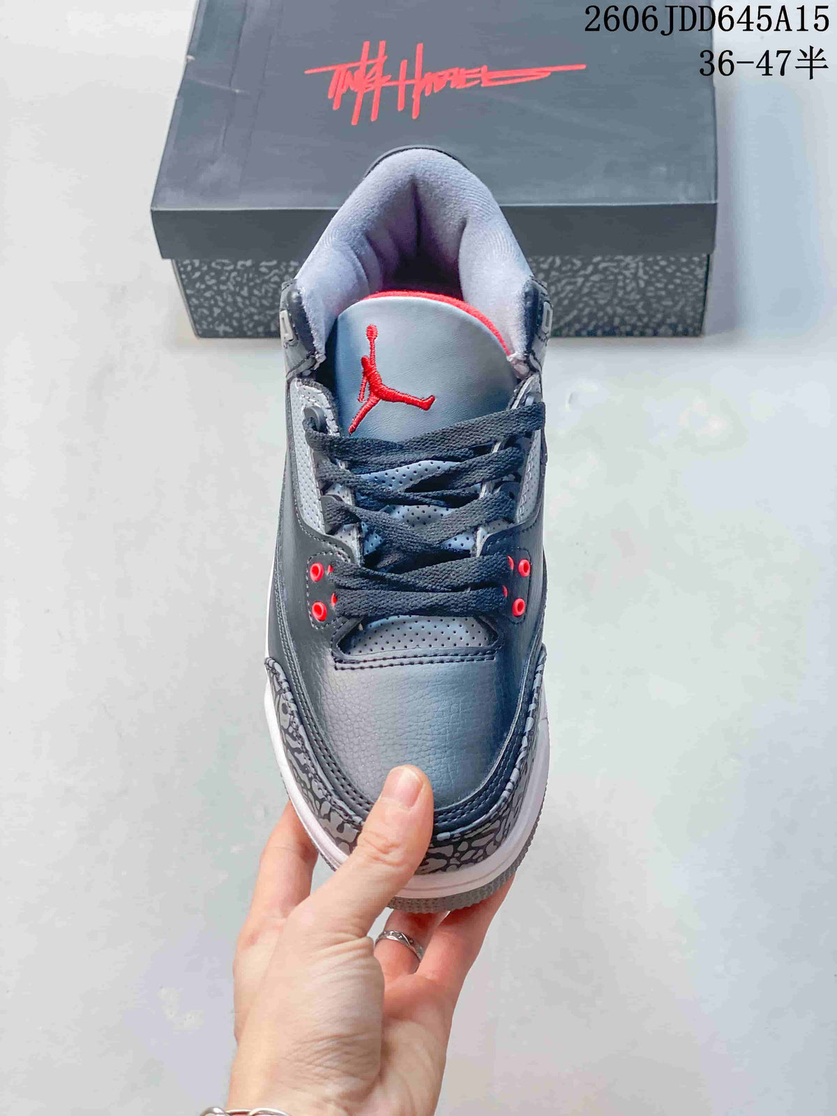 Front view of a grey sneaker showing dark laces, red eyelets, and a red tongue logo.
