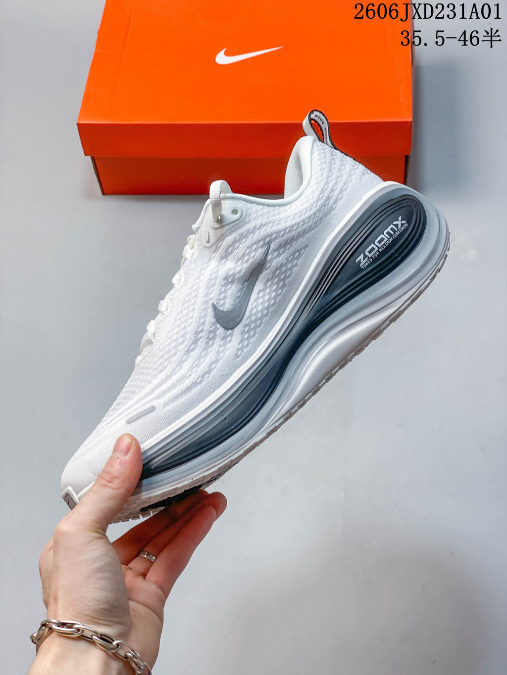 Side view of a white Nike Vomero Plus shoe with gray accents and a dark heel panel.