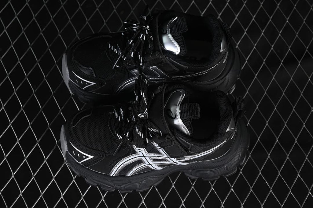 Pair of black sneakers with silver side details, viewed from above.