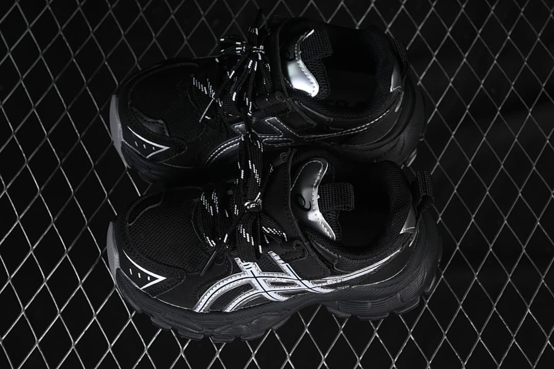 Pair of black sneakers with silver side details, viewed from above.