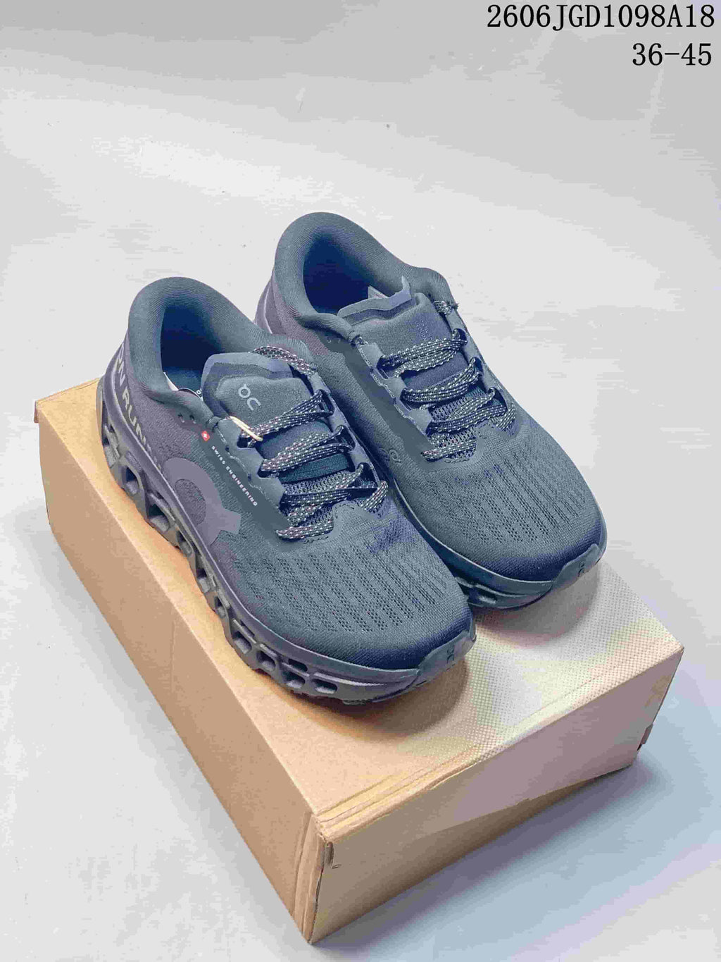 Pair of charcoal-gray On Cloudmonster 3 shoes shown from the front at an angle.