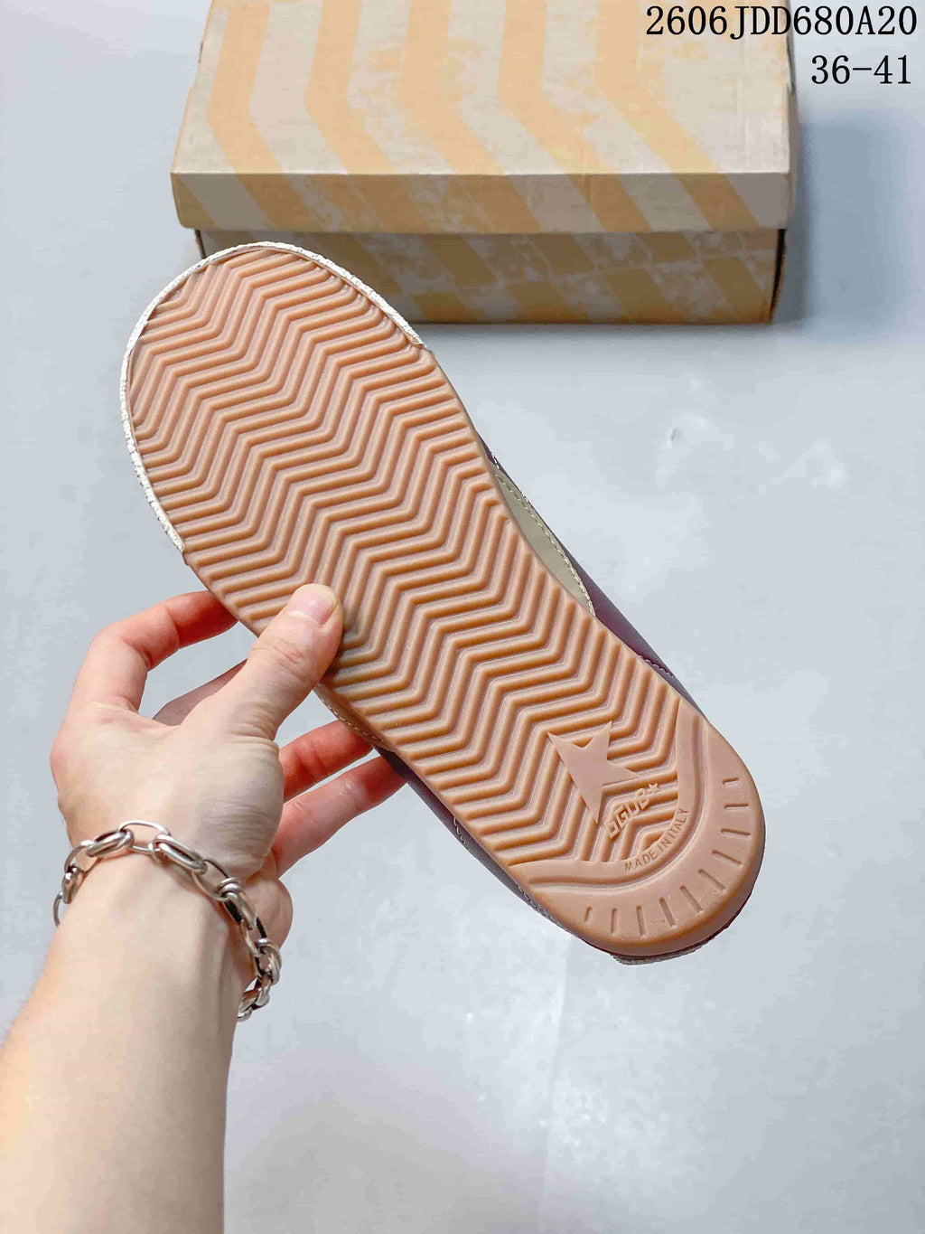 Underside of a sneaker showing a gum-colored outsole with a zigzag tread pattern