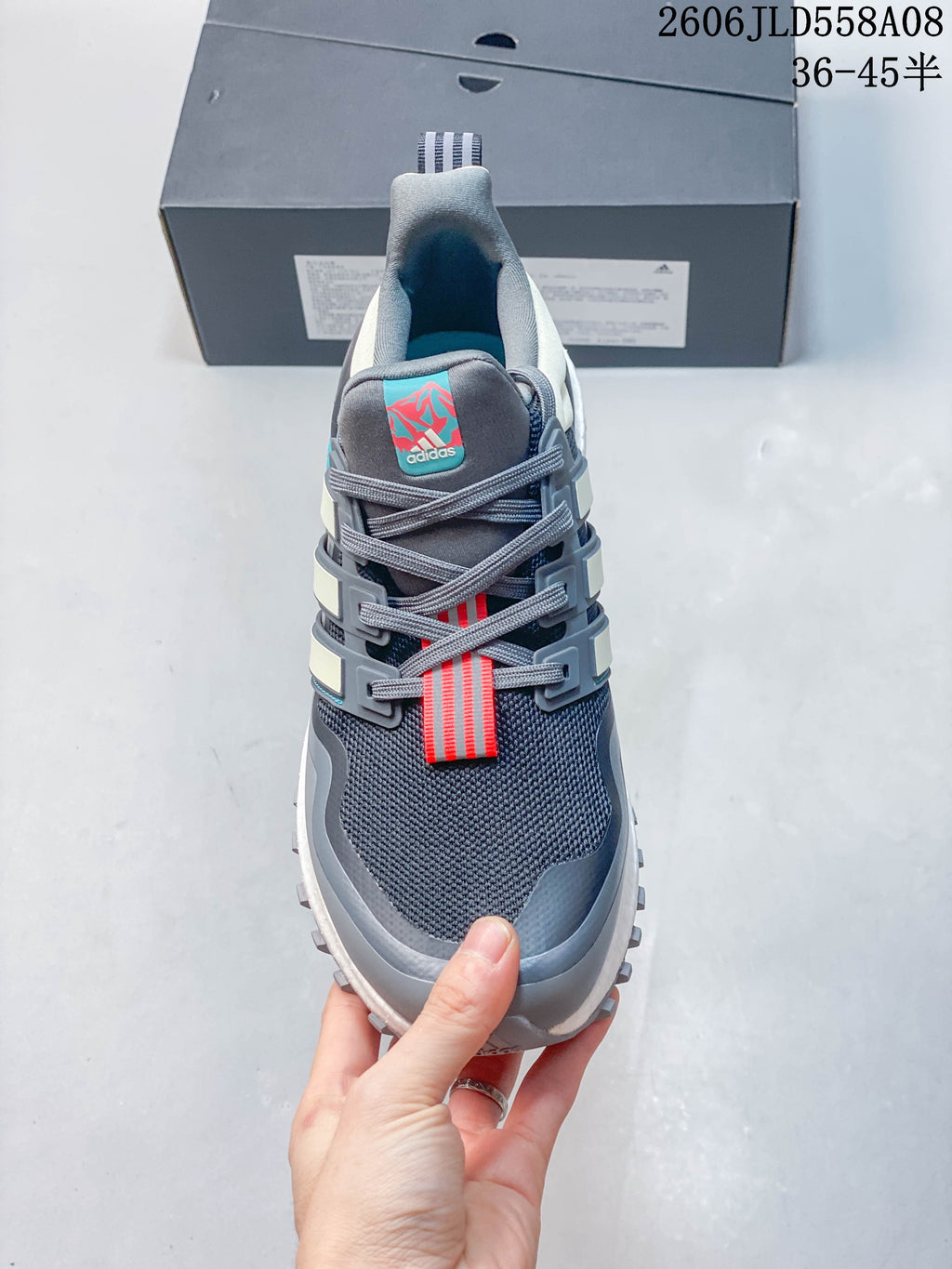 Front view of a grey Adidas sneaker showing its mesh upper, laces, and coral details.