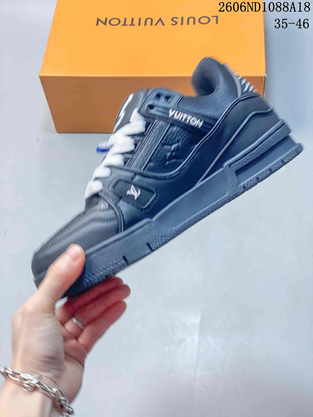 Side view of a dark navy Louis Vuitton Trainer sneaker with monogram-style panels and white laces
