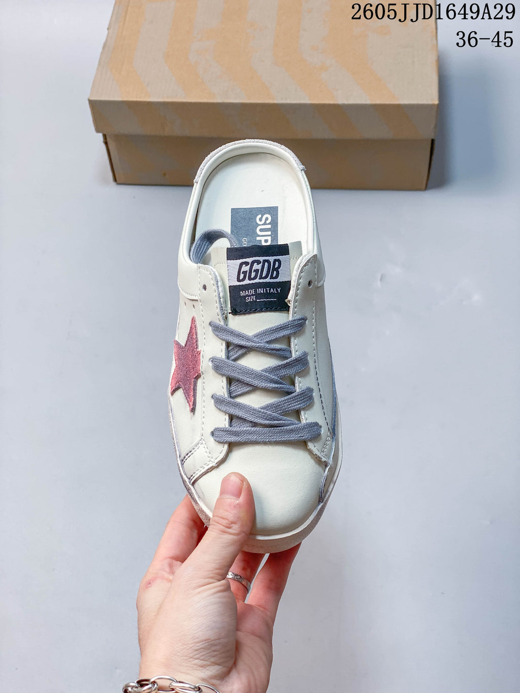 Top view of a white sneaker with gray laces and a pink star detail