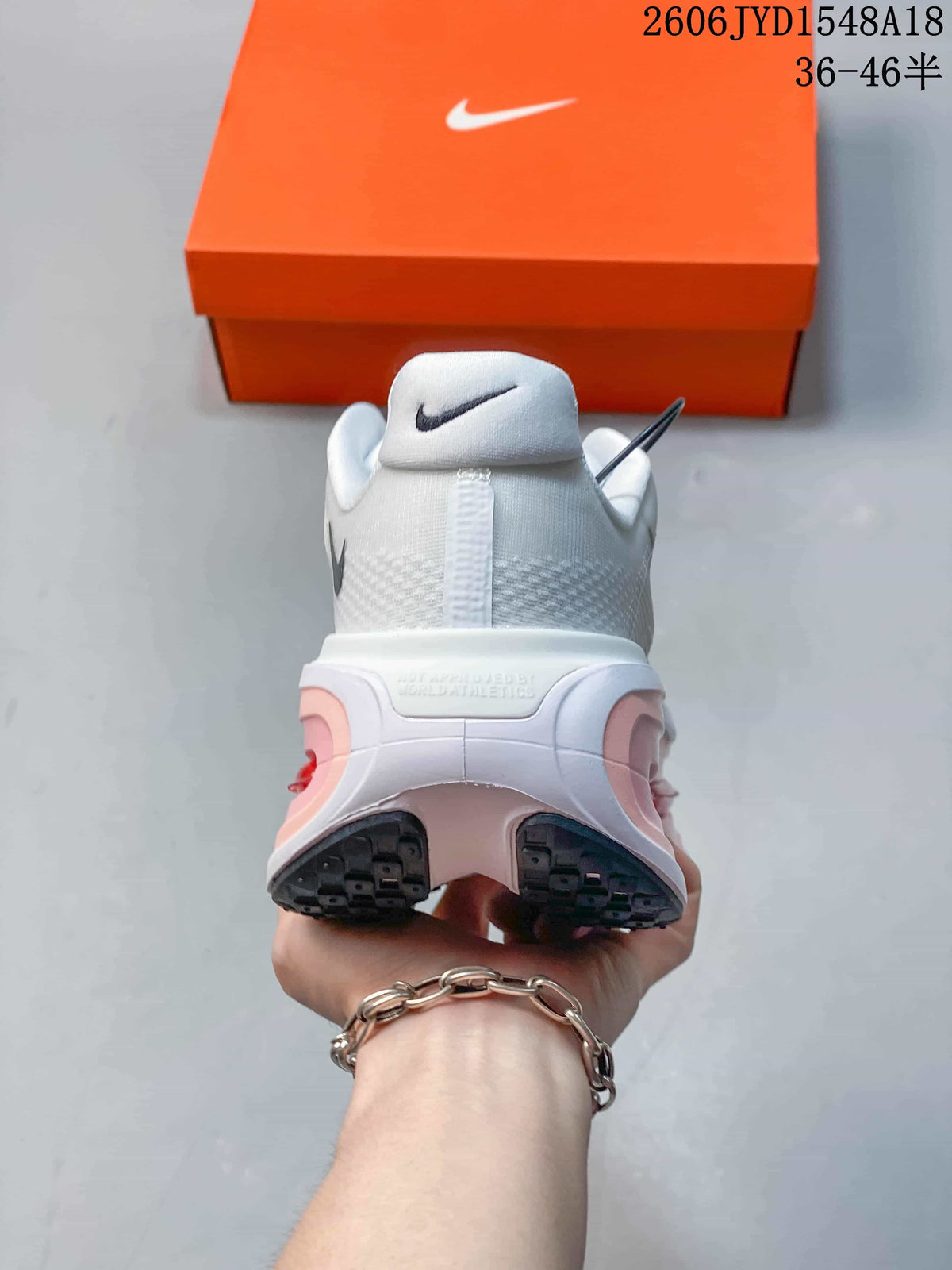 Rear view of a shoe showing the heel, pink cushioning accents, and black outsole.
