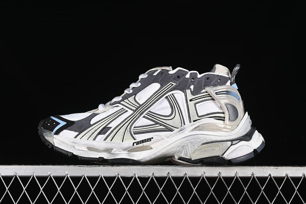 Side view of a beige, white and charcoal Balenciaga Runner sneaker with light blue accents.