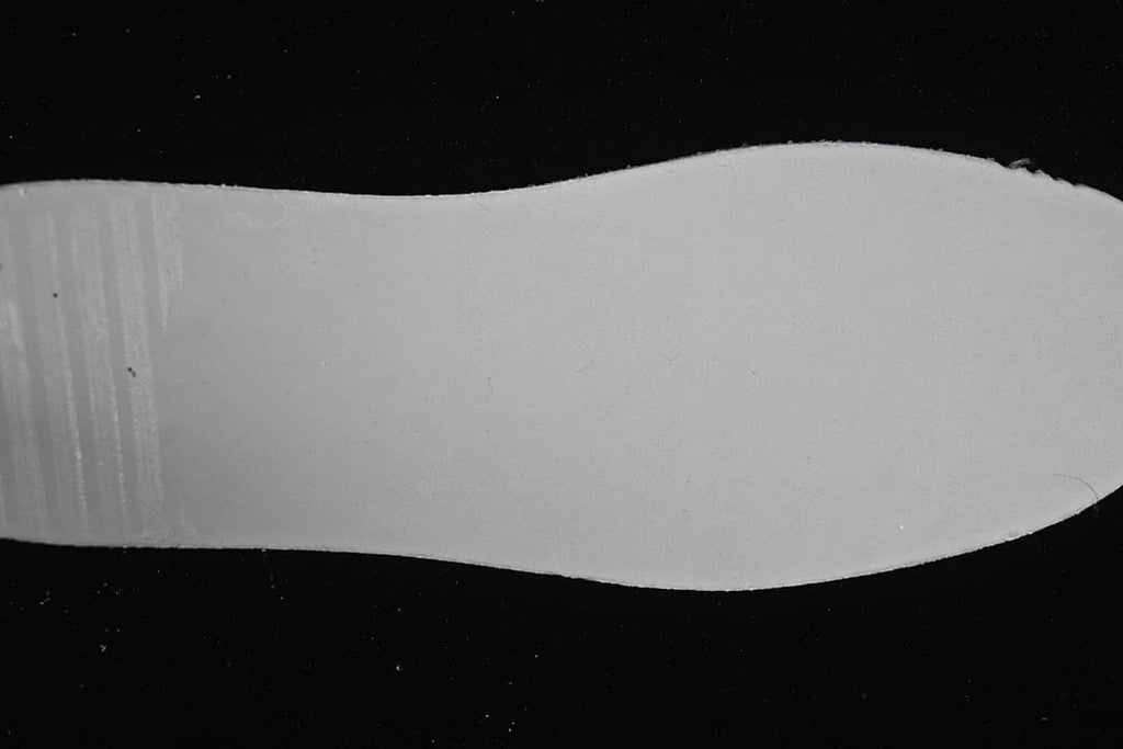 Plain white shoe insert photographed against a dark background