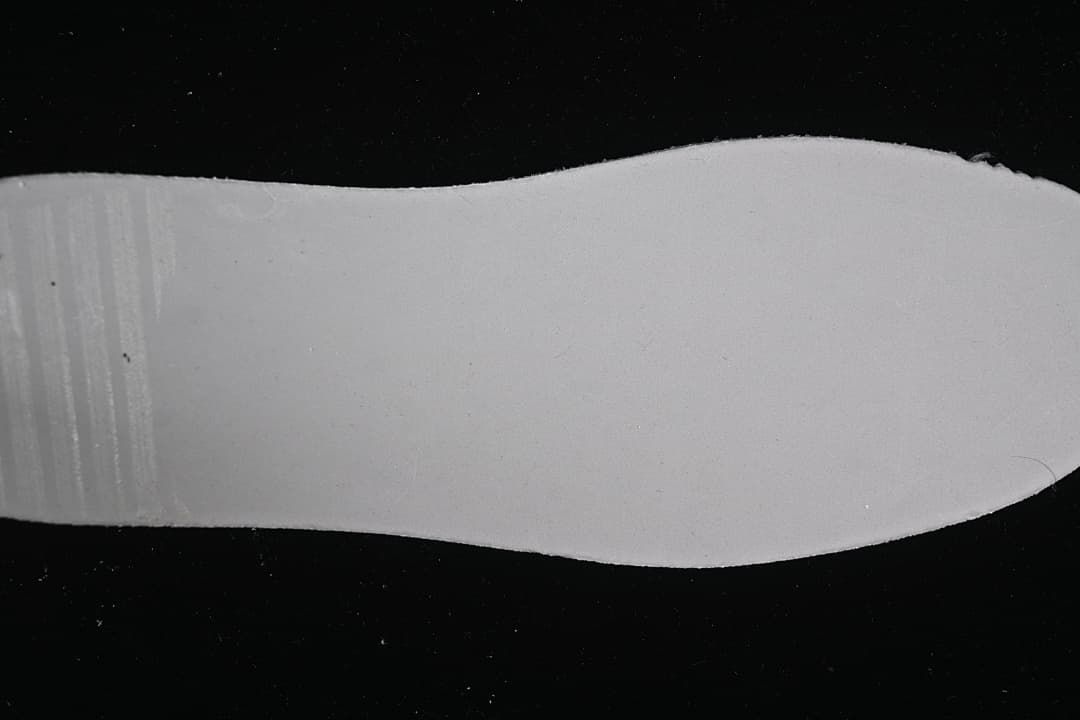 Plain white shoe insert photographed against a dark background