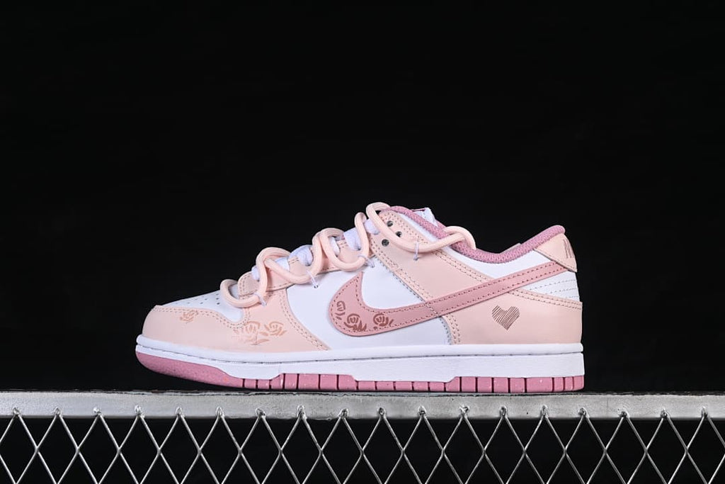 Side view of a white and pink Nike SB Dunk Low sneaker with floral and heart motifs