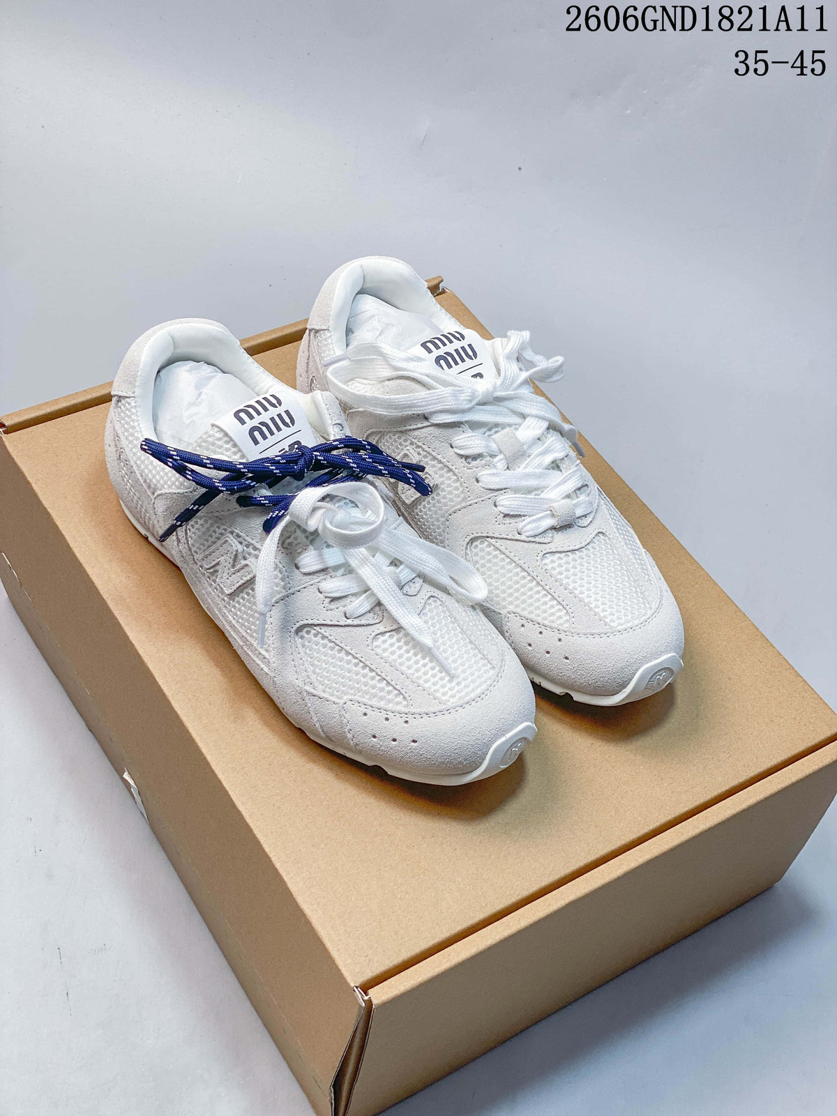Pair of white and light gray 530SL-style sneakers with navy and white laces on a box