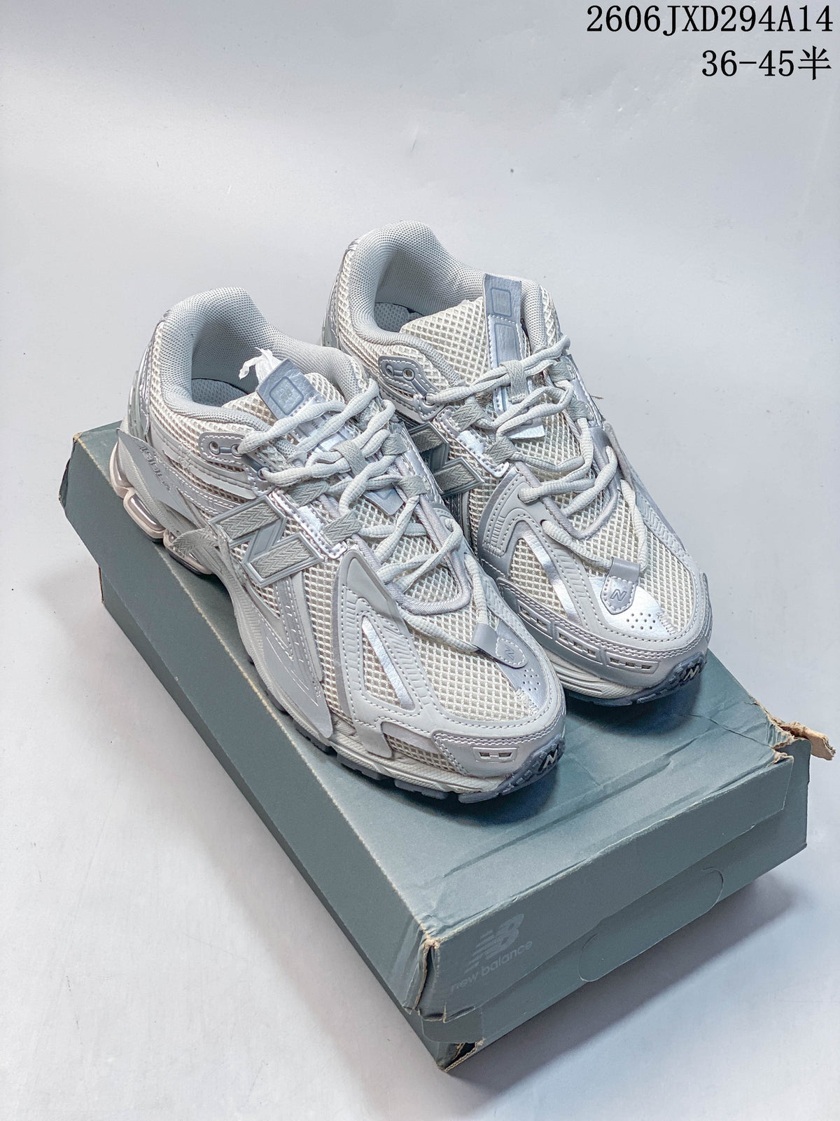 Silver-grey New Balance 1906 sneakers displayed on a shoebox.