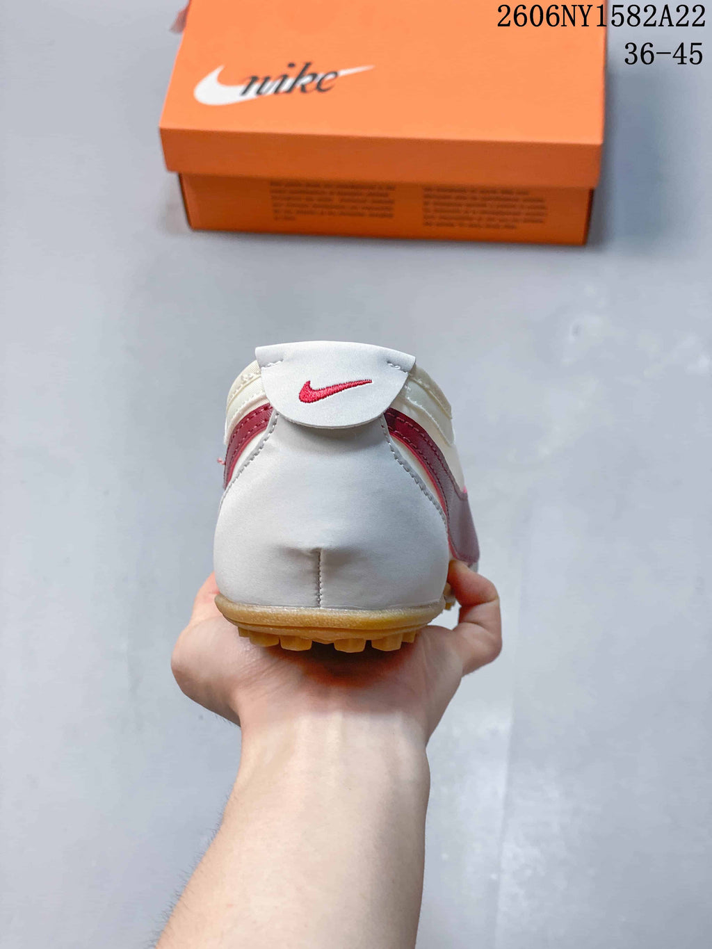 Rear view of the off-white sneaker with red detailing and a gum-colored outsole.