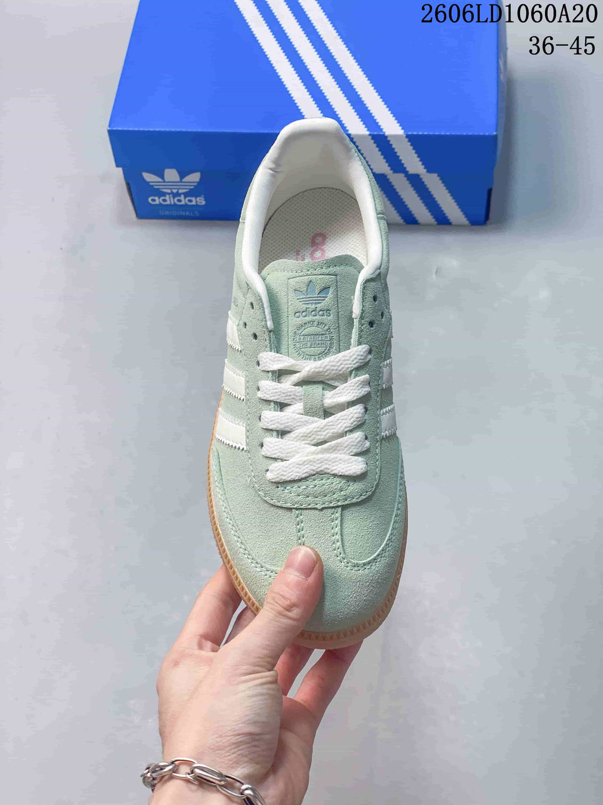 Top view of the sneaker showing white laces, tongue branding, and pale green upper.