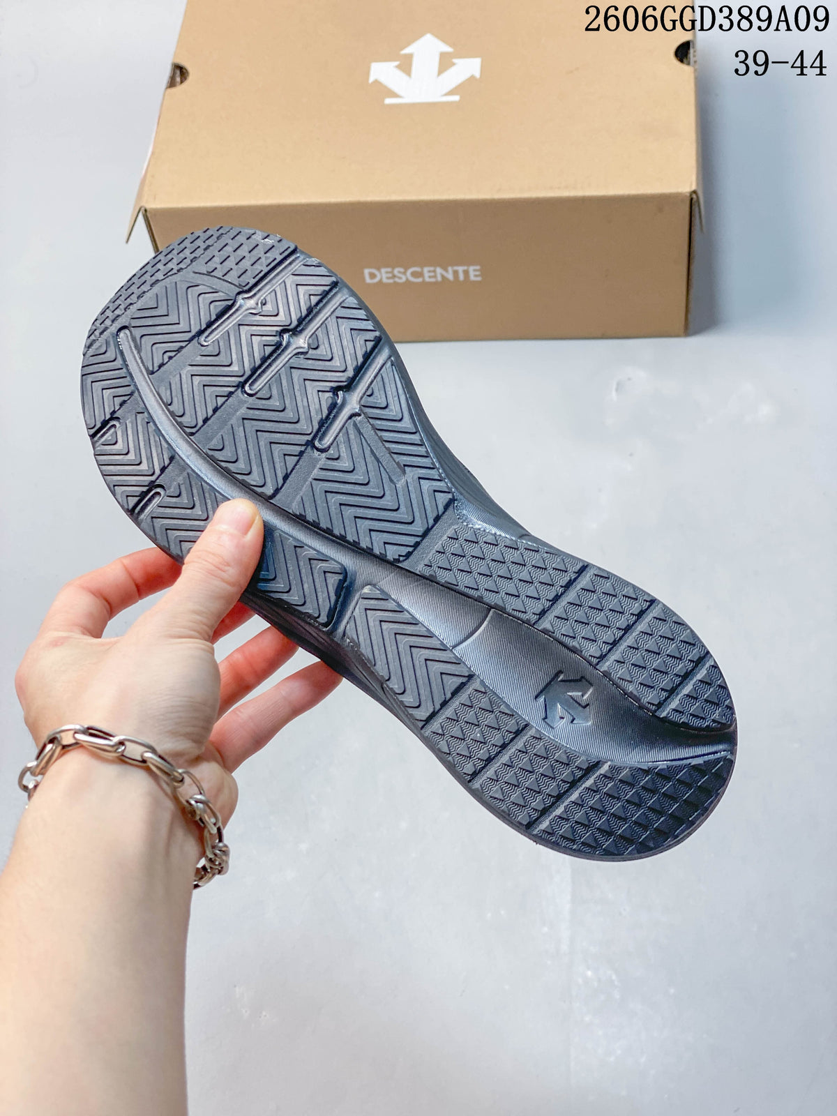 Close-up of the patterned outsole on a dark gray Descente running shoe.