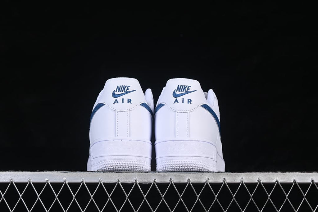 Rear view of white Nike Air Force 1 ’07 sneakers with navy heel details