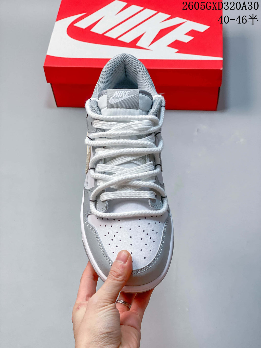 Front view of a white and gray low-top sneaker showing the perforated toe and white laces.