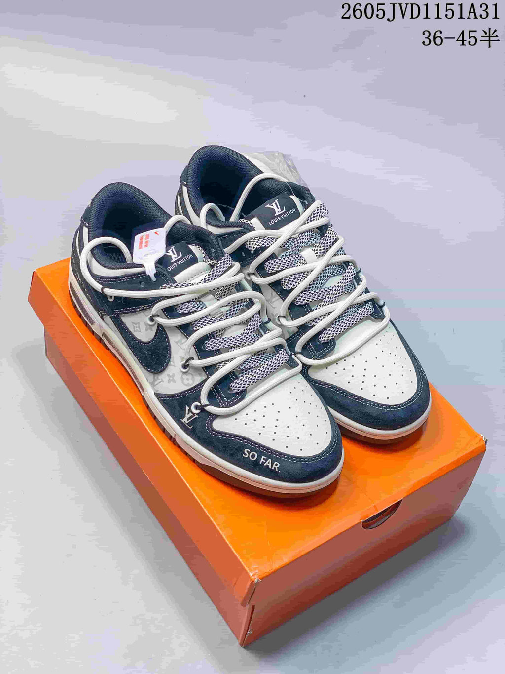 Pair of navy and white low-top sneakers with patterned side panels and layered laces on an orange shoe box.
