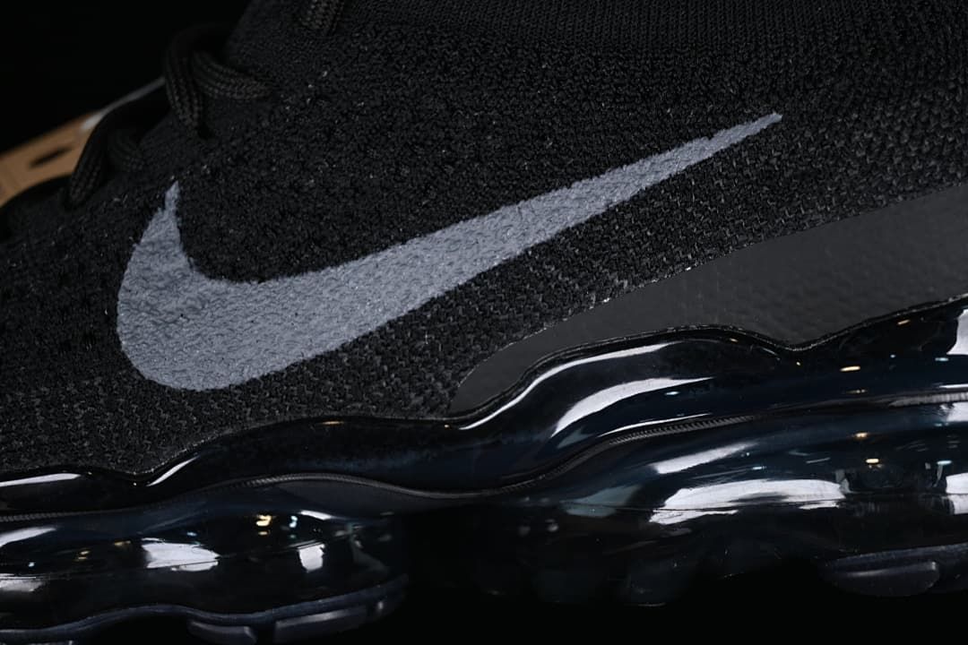 Close-up of the gray Swoosh and dark sole on the black knit upper