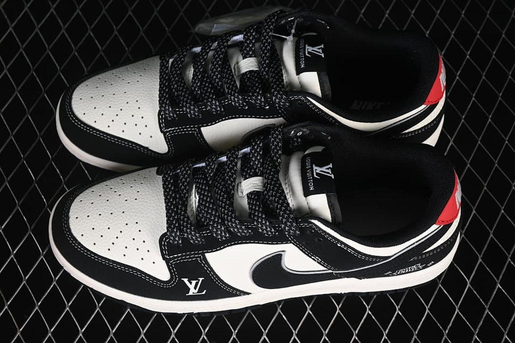 Top view of a pair of black and white low-top sneakers with patterned laces and red heel accents