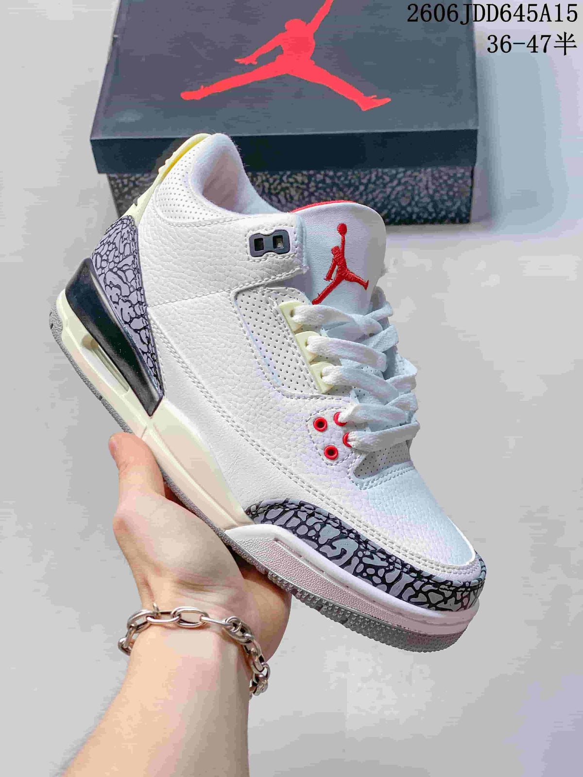 White low-top Jordan sneaker with dark gray patterned overlays, red accents and a Jordan shoebox.