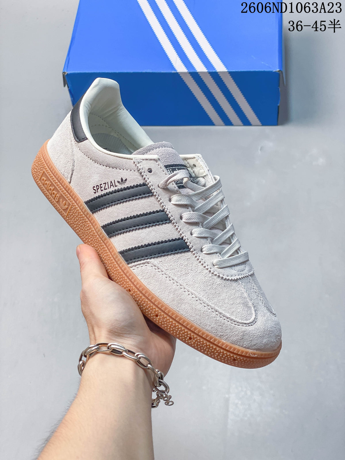 Light grey Adidas Spezial low-top sneaker with dark stripes and a gum-toned sole.