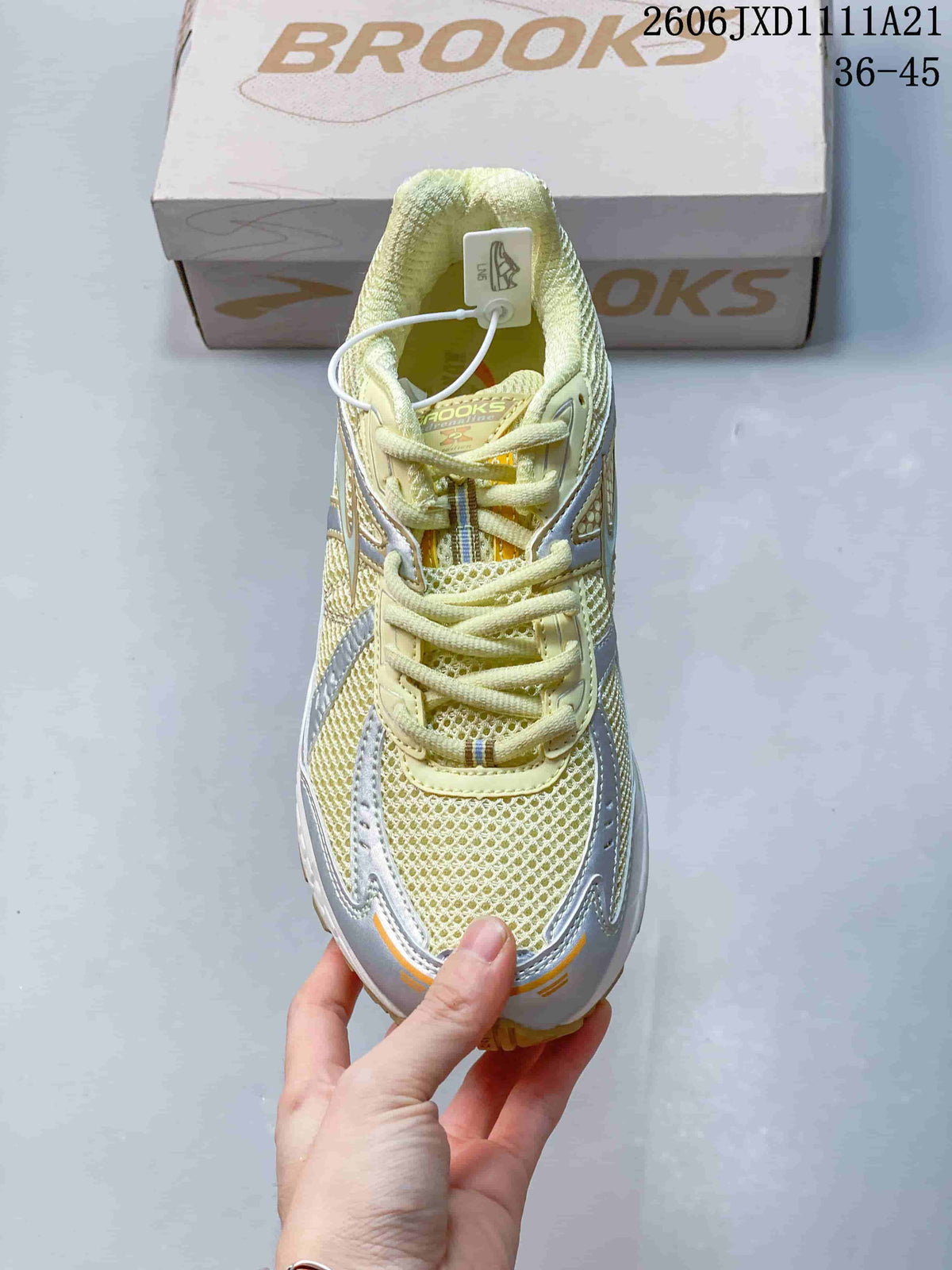 Top view of a lace-up Brooks sneaker with a pale yellow mesh-look upper