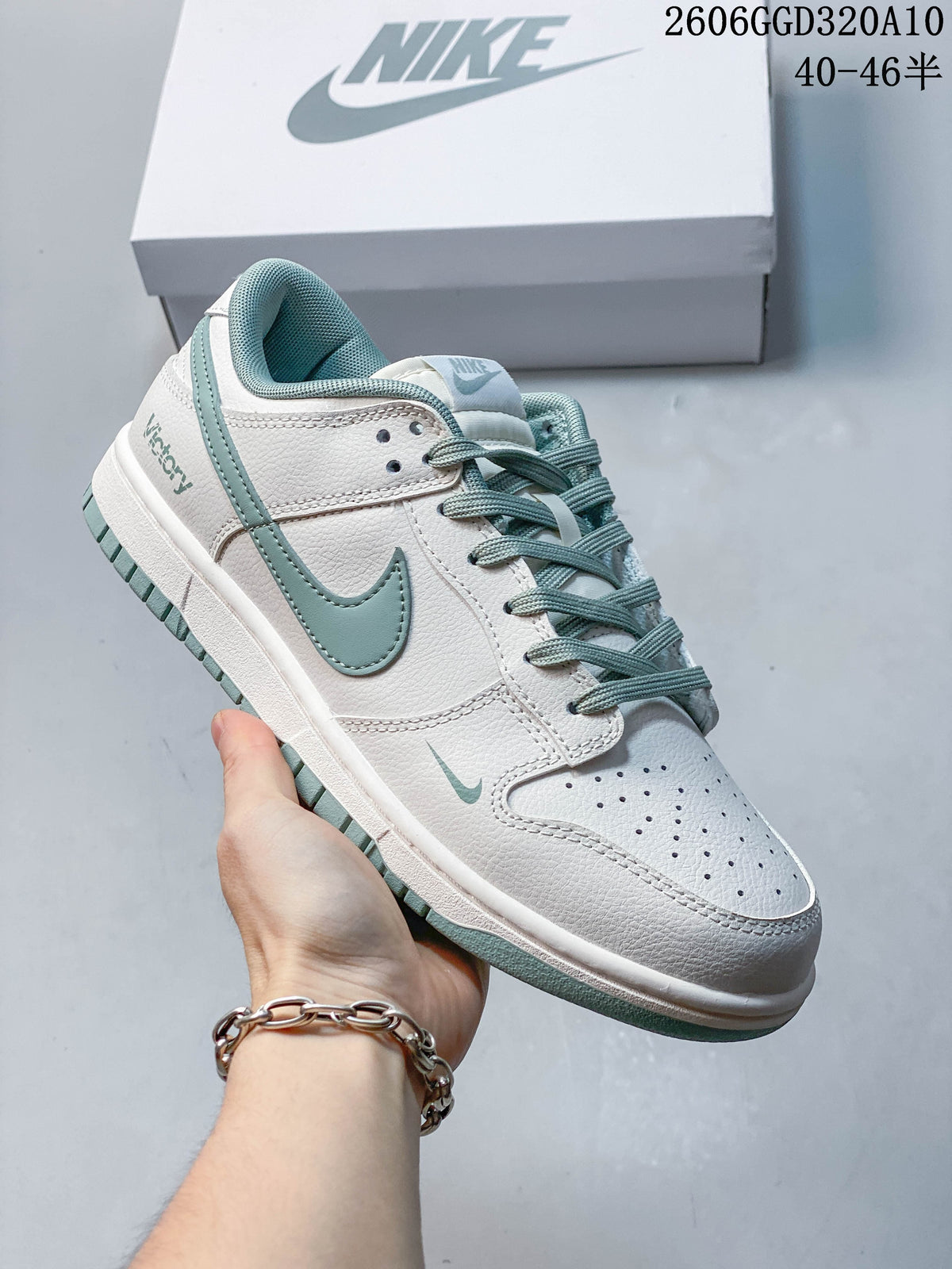 Angled side view of a white Nike Dunk Low Retro sneaker with sage accents and laces.