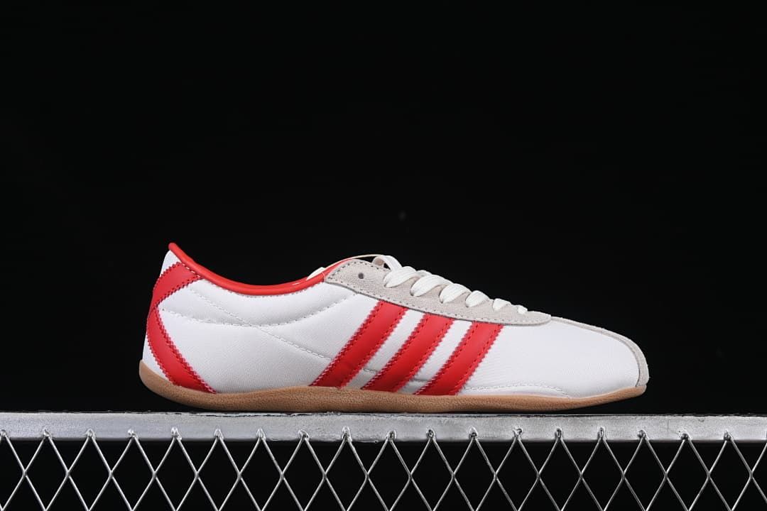 Side profile of the white sneaker with red stripes and gum-colored outsole