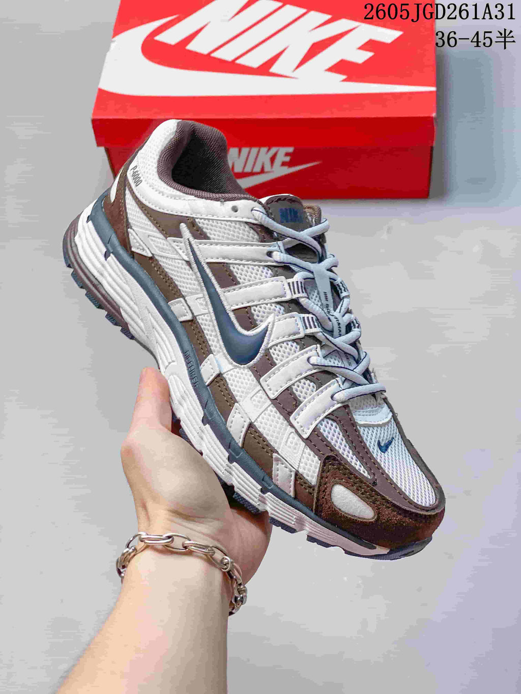 Side view of a white Nike P-6000 sneaker with brown and blue-gray accents.