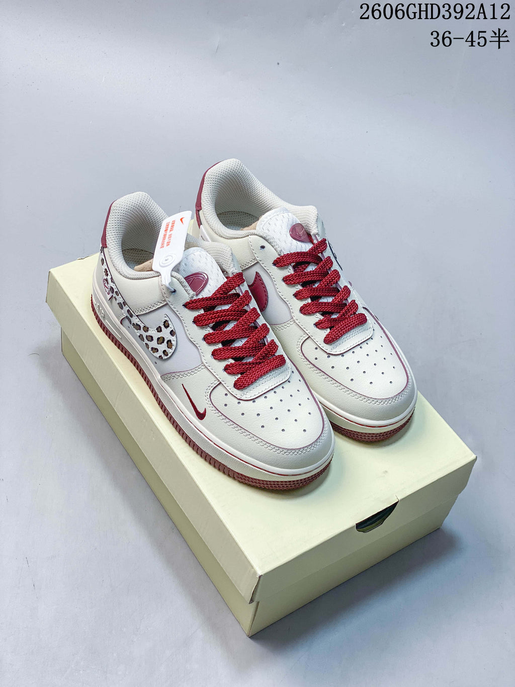 Pair of off-white and burgundy Nike Air Force 1 sneakers with leopard-print Swoosh panels