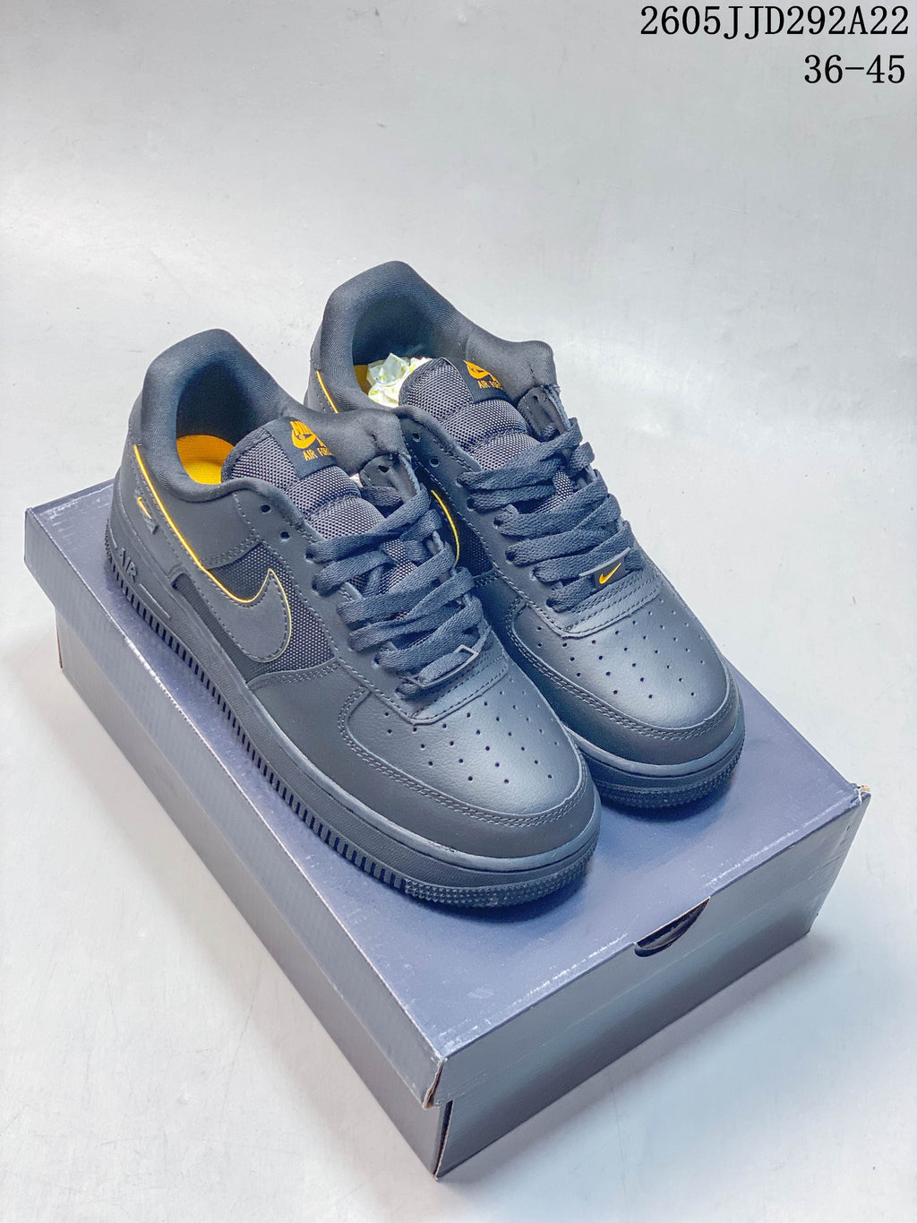 Pair of gray Nike low-top sneakers with yellow accents on a shoebox