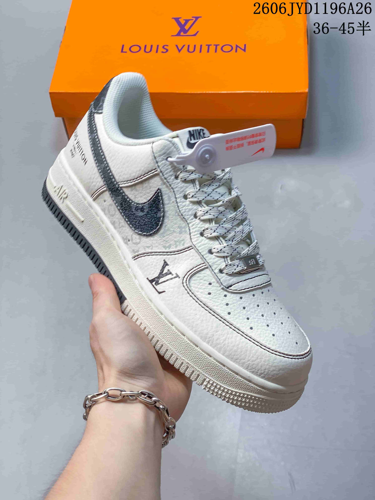 White low-top sneaker with a dark side detail, patterned laces, and monogram-style markings, held in front of an orange box.