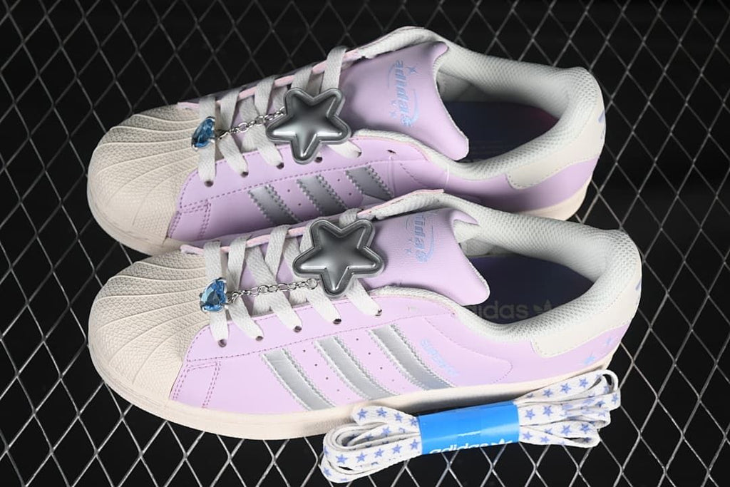Pair of lilac-pink Superstar sneakers with charms and a spare patterned lace set