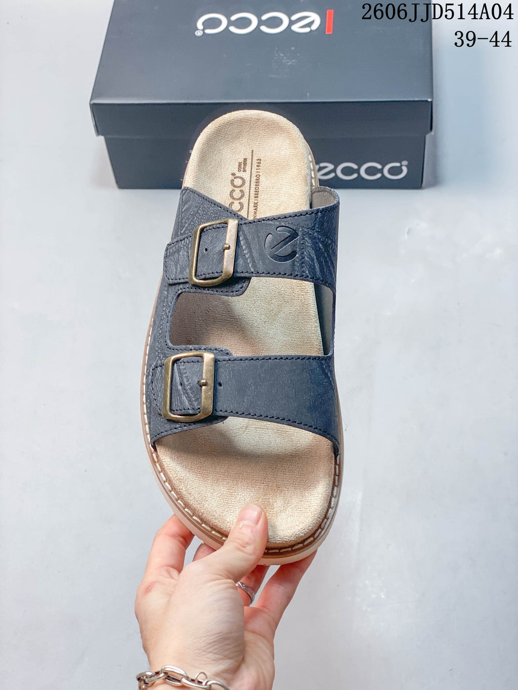 Top view of the blue slide sandal, showing two buckle straps and a light-colored footbed; image overlay shows style code 2606JJD514A04 and sizes 39–44.