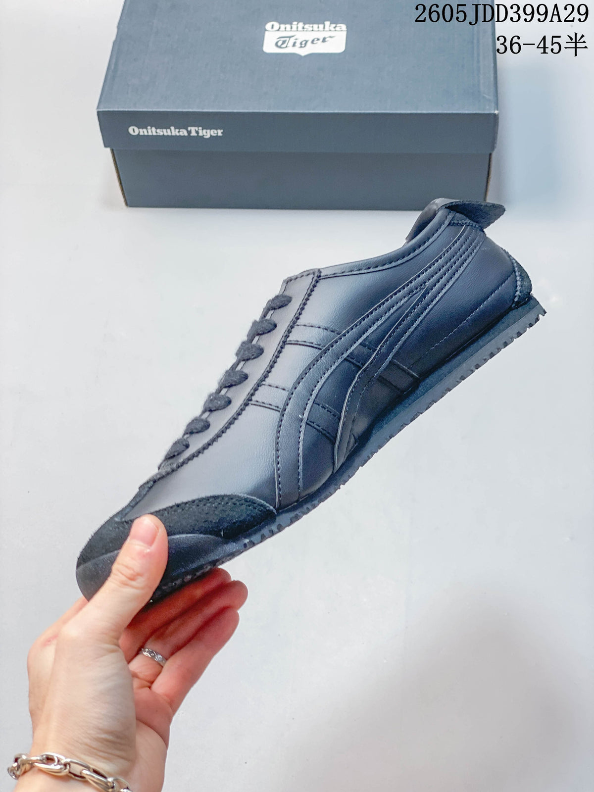 Side profile of a gray Onitsuka Tiger low-top sneaker with dark toe overlay and side stripes.