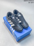 Navy Adidas Originals Taekwondo sneakers with white stripes and laces, shown on a blue shoe box