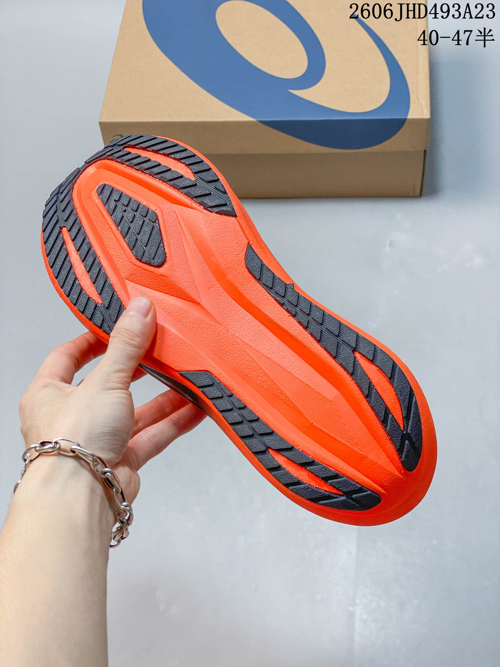 Underside of an orange running shoe showing a dark contrasting outsole