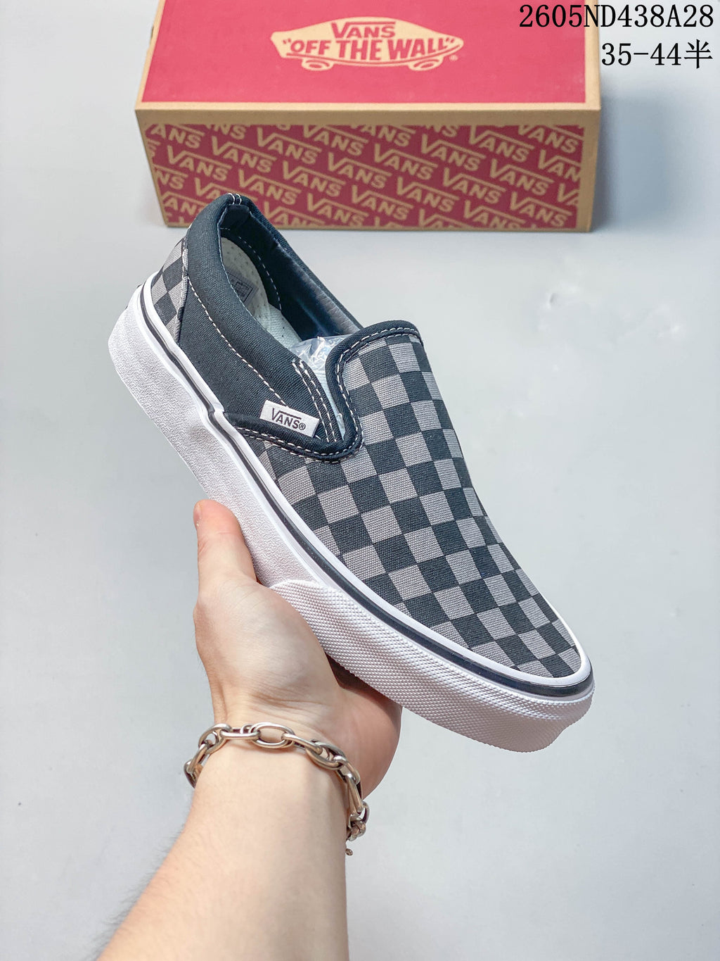 Angled view of the checkerboard slip-on sneaker and its side tag