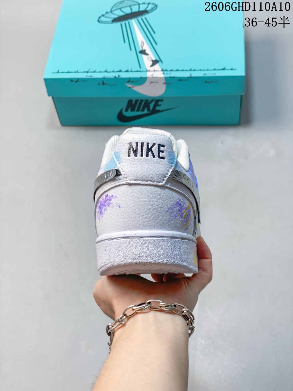 Rear view of a white sneaker with purple artwork and a Nike heel tab.
