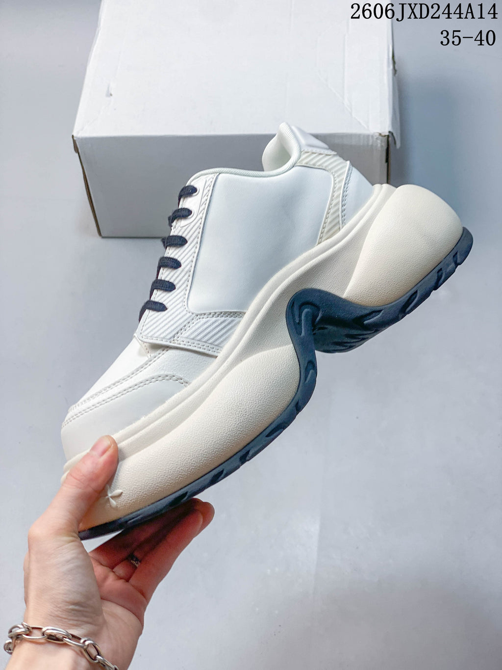 Side profile of the white sneaker with a sculpted midsole and dark outsole; image overlay shows code 2606JXD244A14 and sizes 35–40.