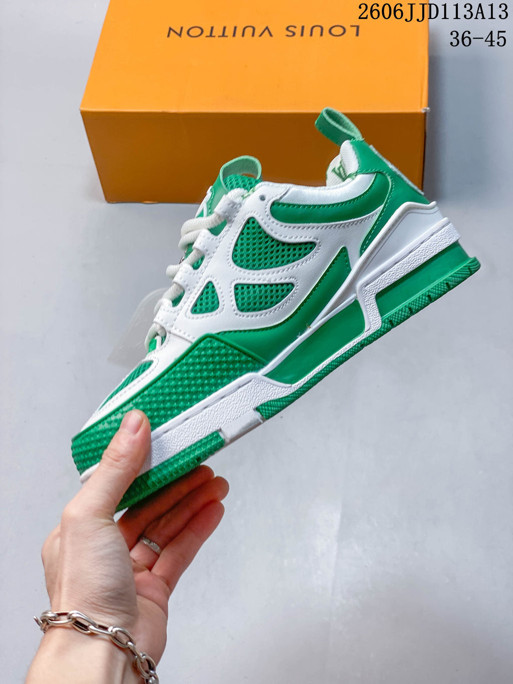 Side profile of a green and white sneaker with mesh inserts and layered overlays.
