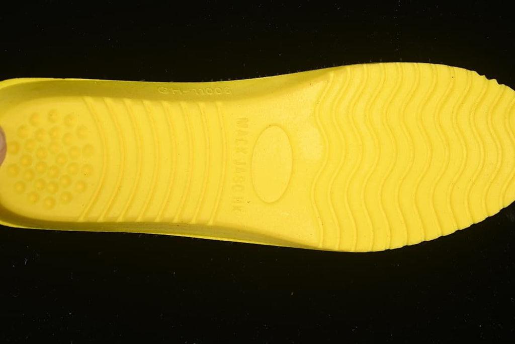 Underside view of a bright yellow shoe insert with molded wavy grooves.
