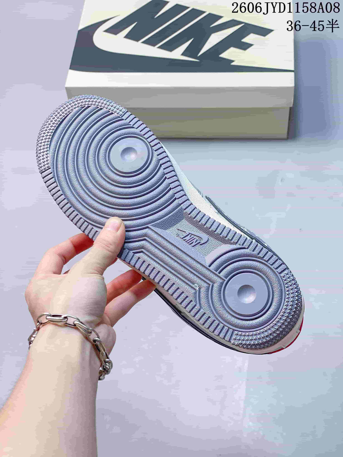 Underside of a gray sneaker showing a circular-patterned outsole and Nike mark