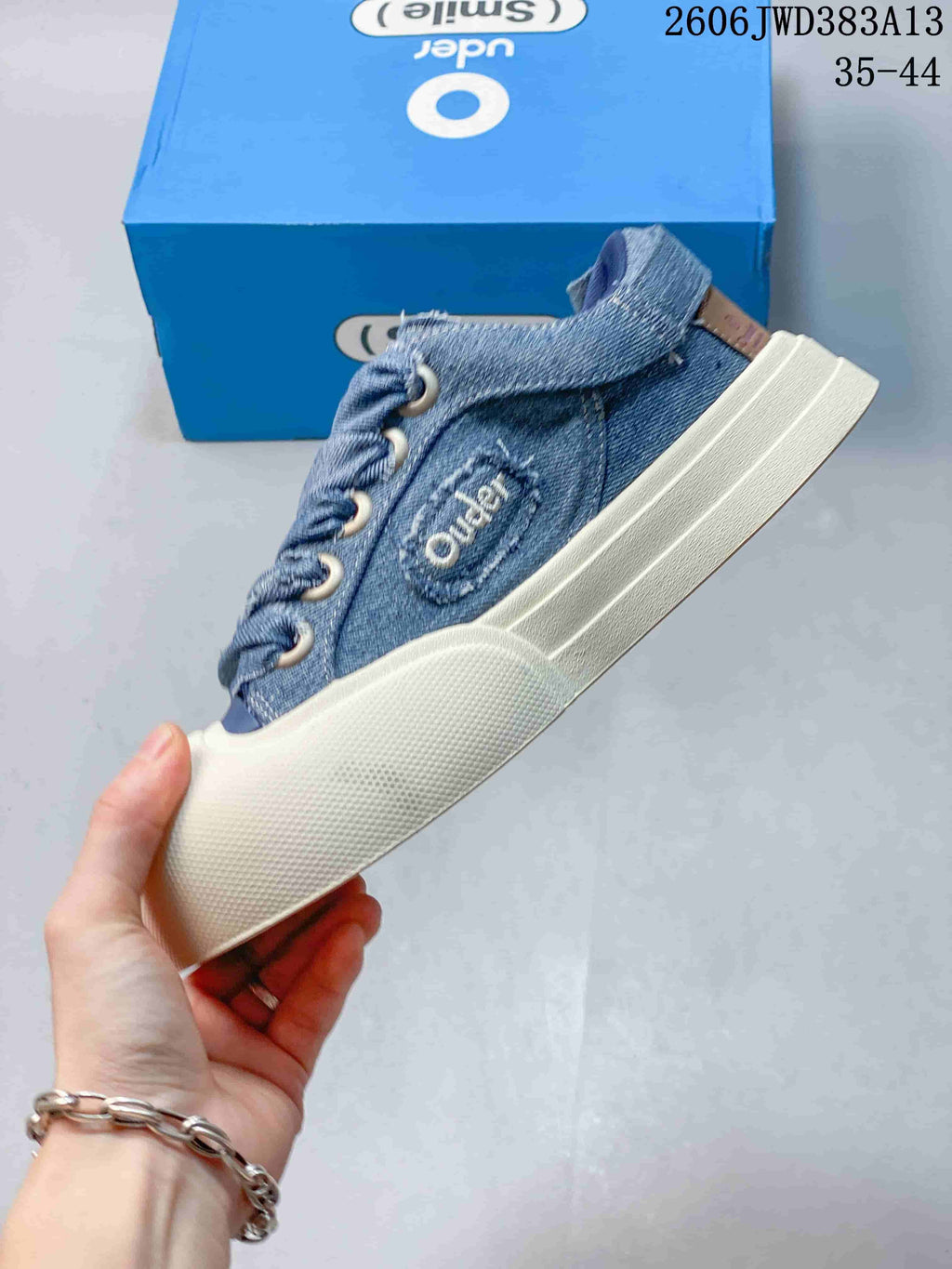 Side view of a blue denim Ocai Smile low-top sneaker with a thick white sole.