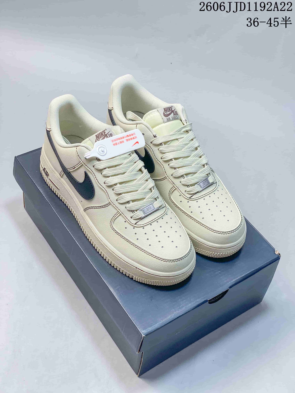 Pair of cream low-top sneakers with dark swooshes and contrast stitching