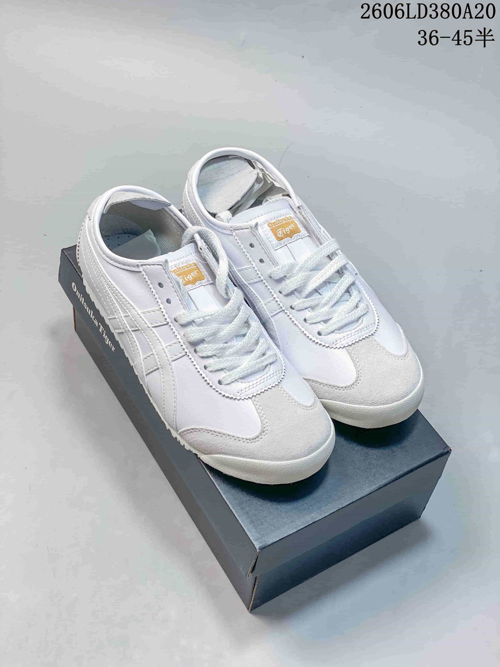 Pair of white low-top sneakers with white side stripes, displayed on a shoe box.
